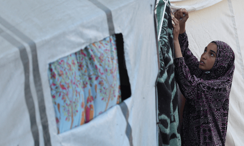  A Palestinian woman displaced by the Israeli military offensive hangs a blanket in a shelter at an UNRWA school in Deir Al-Balah, in the central Gaza Strip on August 20, 2025. &mdash; Reuters 
