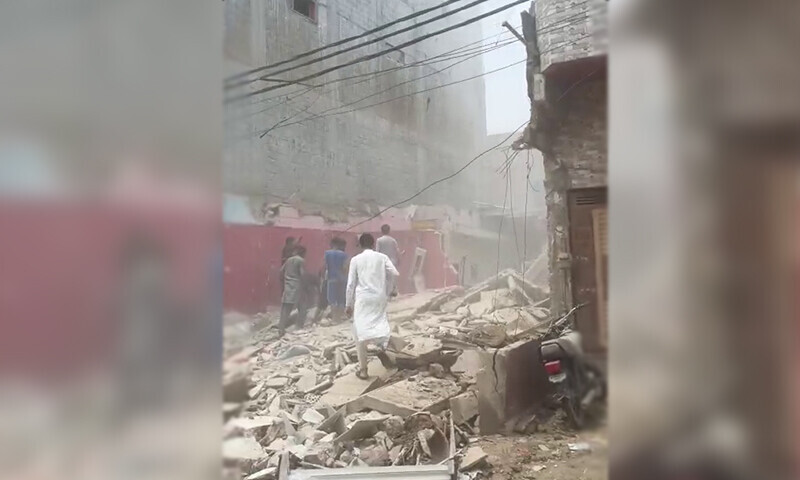 People stand in the rubble of the two-storey building which completely destroyed in a gas explosion in Orangi Town in Karachi on August 20. &mdash; DawnNewsTV