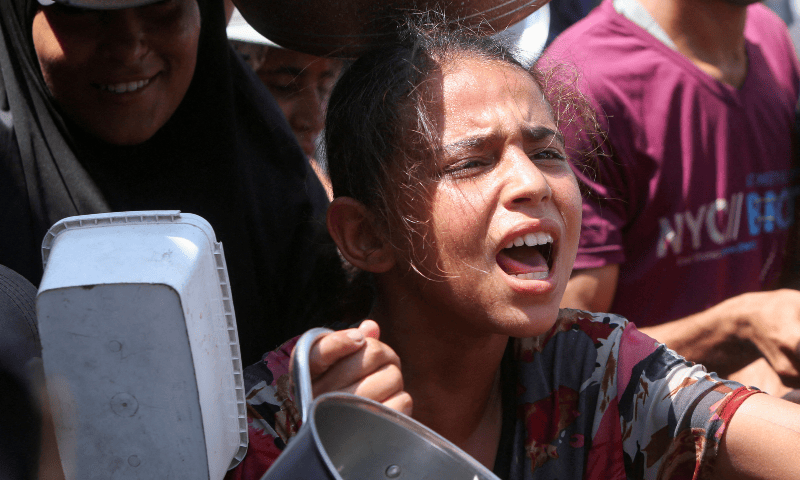 A girl reacts as she and other Palestinians wait to receive food from a charity kitchen in Khan Younis, southern Gaza Strip on August 21, 2025. — Reuters