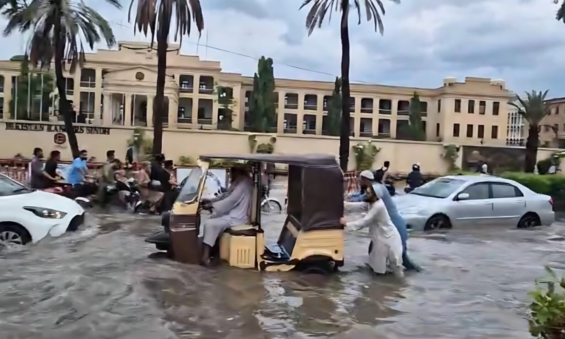 Two men push a rickshaw through flooded streets.
