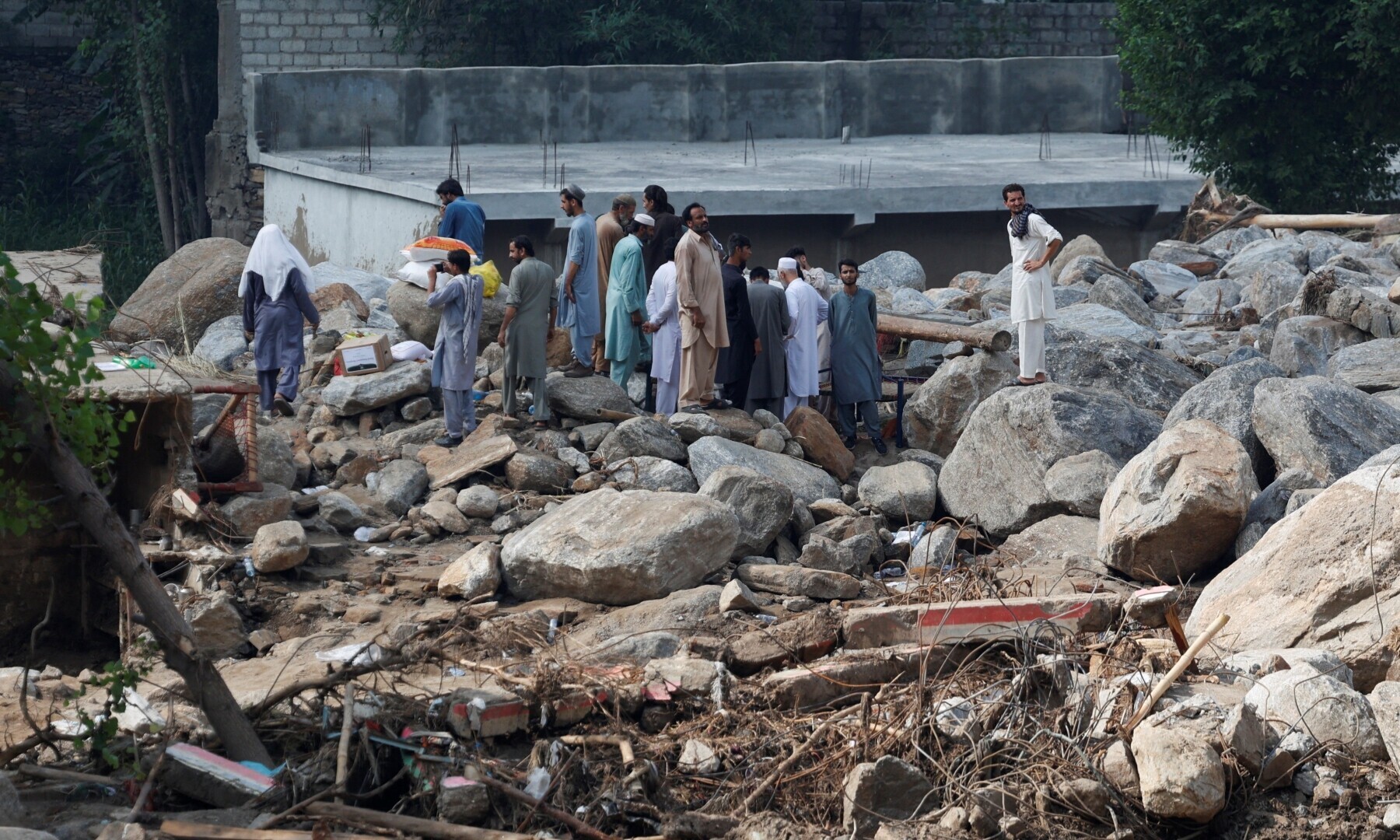 Residents gather near a house damaged by rocks and boulders, following a storm that caused heavy rains and flooding in Qadir Nagar area, in Buner district, Khyber Pakhtunkhwa province on August 21. &mdash; Reuters