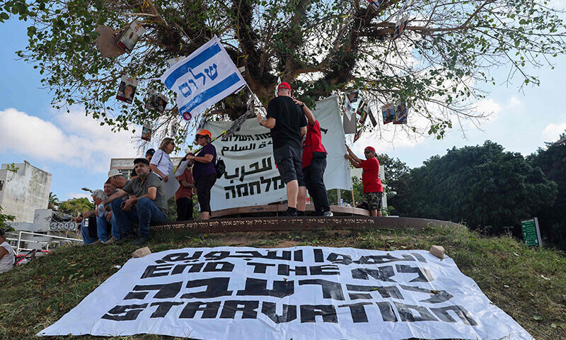 Demonstrators stand under portraits hanging from a tree of Israeli hostages held in the Gaza Strip since the October 7, 2023 attacks, behind a banner reading &lsquo;End Starvation&rsquo;, during a protest by Arab-Israeli and Israeli left-wing activists at HaBima square in Tel Aviv, Israel on August 23, against the ongoing conflict and catastrophic humanitarian situation in the Gaza Strip. &mdash; AFP