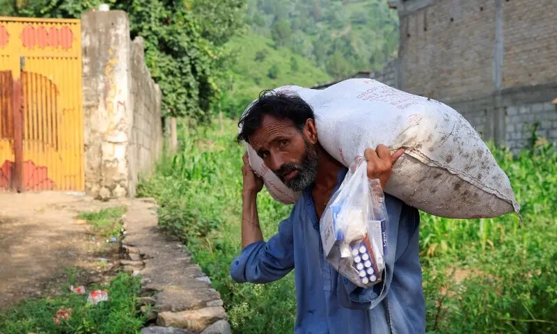 A man carries a sack of relief handouts and medicines, following a storm that caused heavy rains and flooding in Qadir Nagar area in Buner district in Khyber Pakhtunkhwa on August 21. &mdash; Reuters
