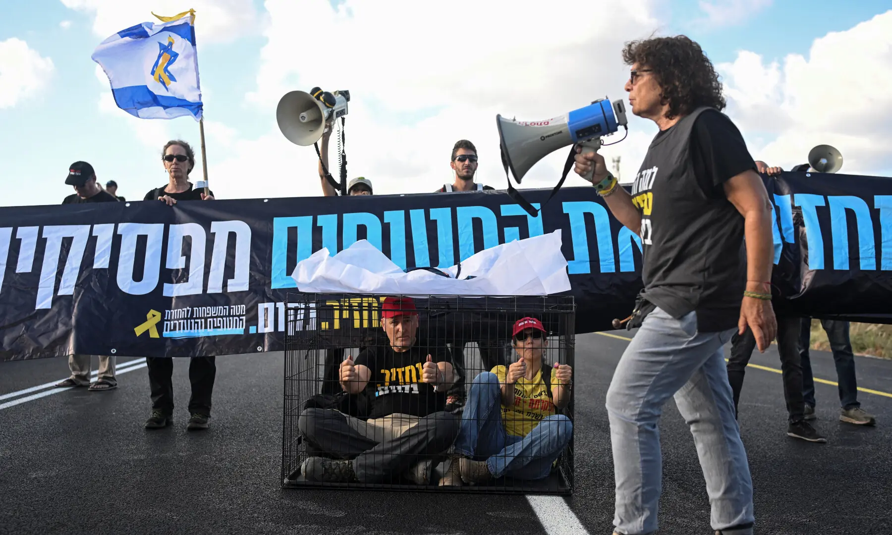  Protesters sit in a cage as they block a main road during a demonstration demanding the immediate end of the offensive and the release of all hostages who were kidnapped during the October 7, 2023 attack, near Habonim, Israel on Aug 26, 2025. &mdash; Reuters/Rami Shlush 