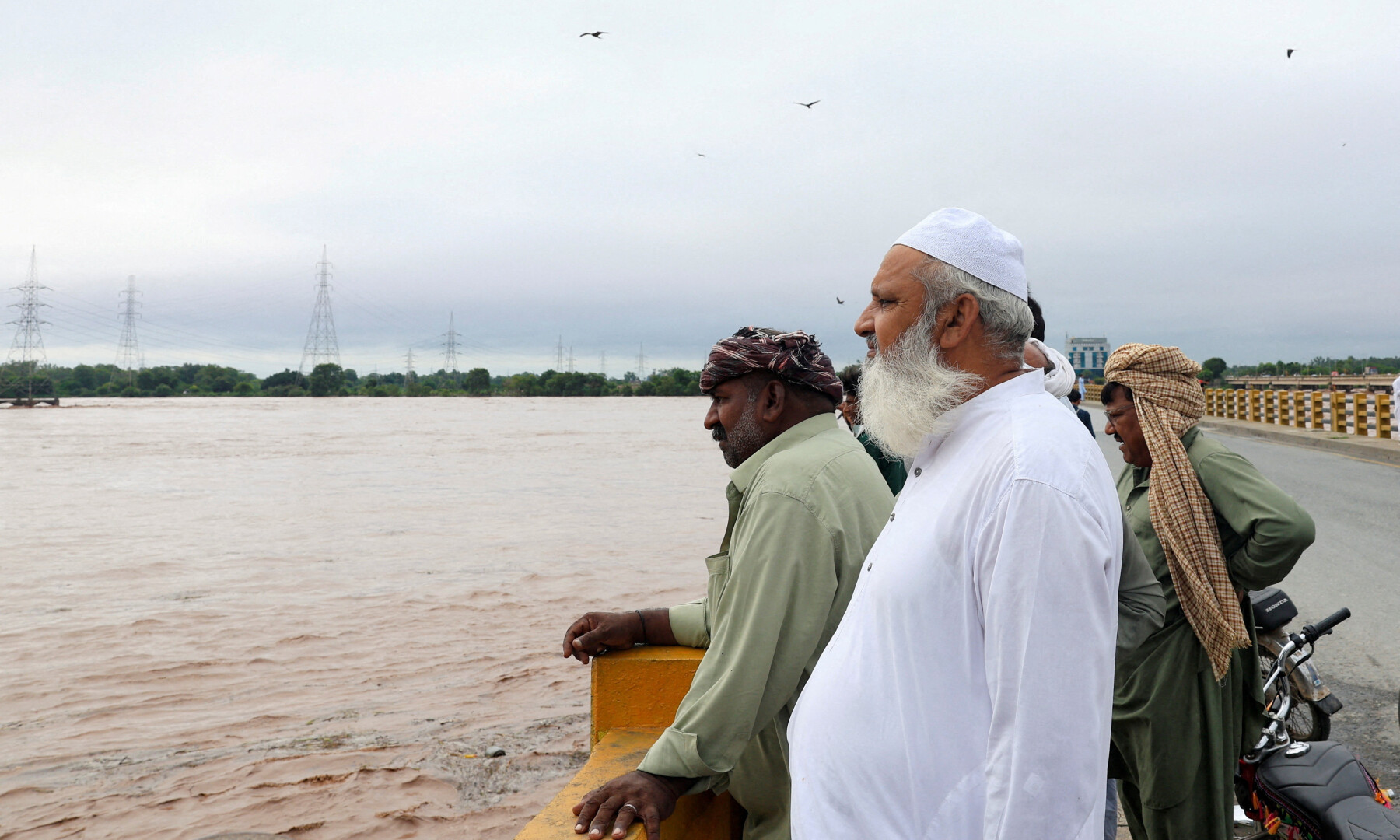 Men stand on a bridge over the Chenab River, following the monsoon rains and rising water level in Wazirabad, in Punjab on Aug 27, 2025. Reuters/Akhtar Soomro