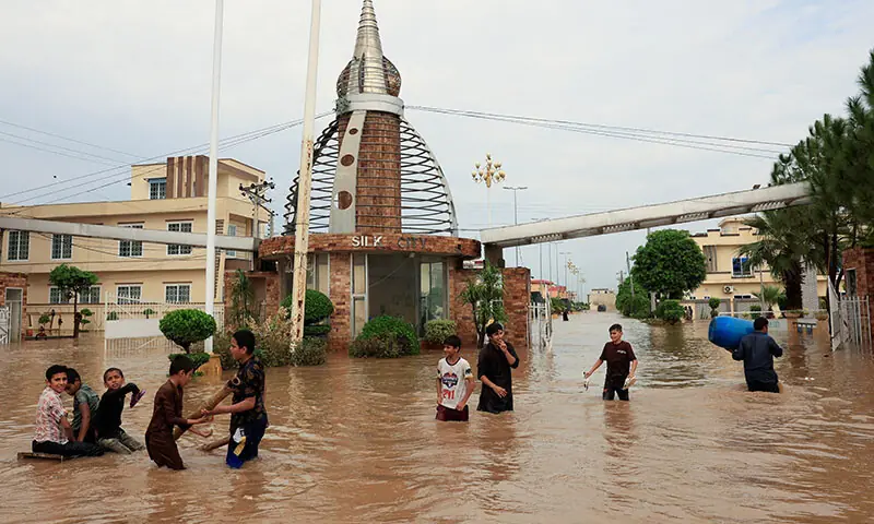 Residents wade through a flooded street in Sialkot on August 27. &mdash; Reuters
