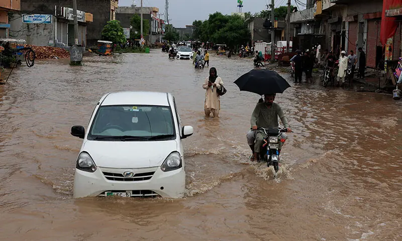 Vehicles move along a flooded street in Sialkot on August 27. &mdash; Reuters
