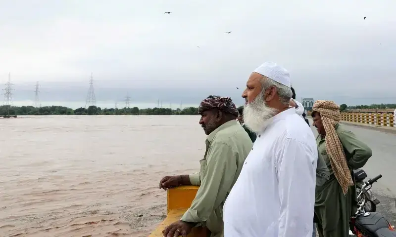 Men stand on a bridge over the Chenab River, following the monsoon rains and rising water level in Wazirabad, in Punjab on August 27. — Reuters