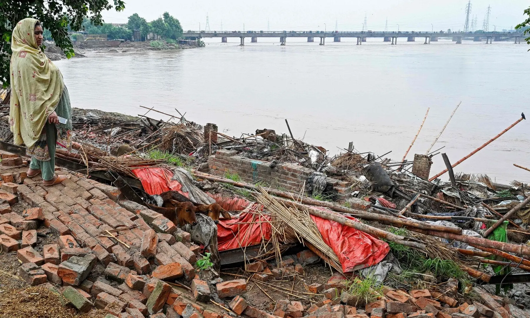  A woman stands over the remains of a collapsed house overlooking river Ravi, as water levels surge after heavy monsoon rain showers in Lahore on August 30, 2025. &mdash; AFP 