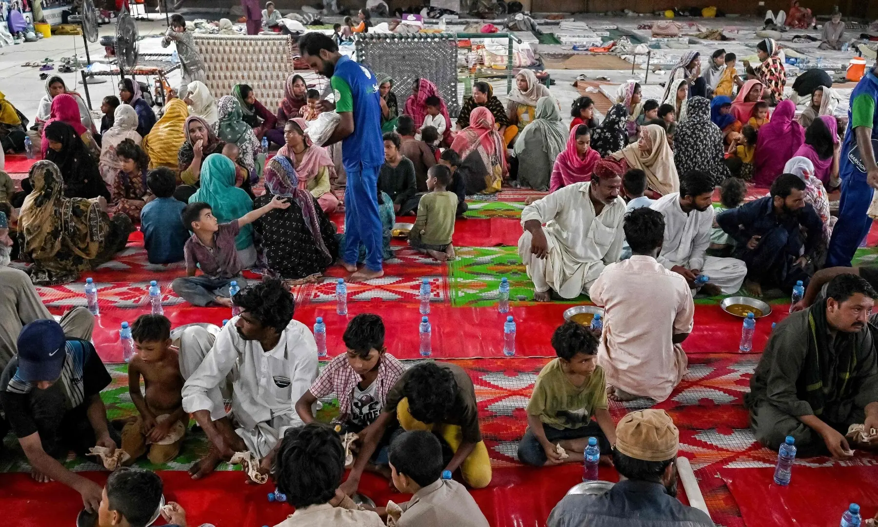  Flood-affected victims eat lunch at a makeshift shelter inside a school in Lahore on August 30, 2025. &mdash; AFP 