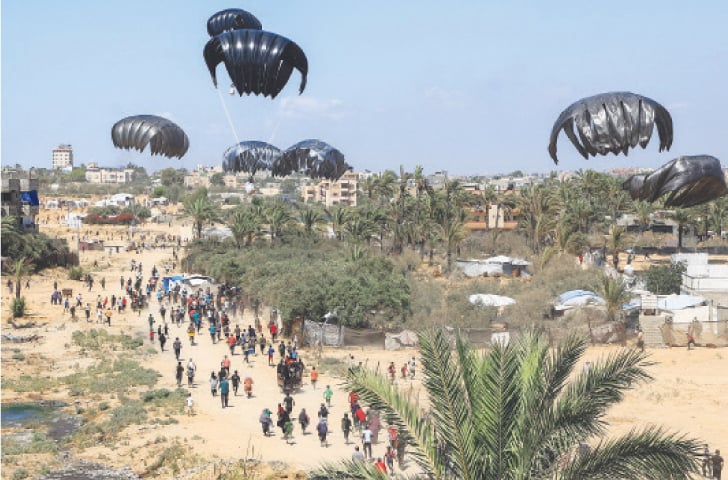  GAZA: Palestinians rush towards aid packages being airdropped over the besieged enclave.—Reuters 