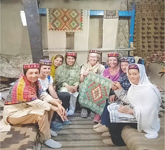 Visitors pose alongside the female workers at the Korgah Carpet Centre in Hunza: women in the region point out the changes they’ve observed due to the increase in female-led tourism and the impact this has had on local women-led businesses | Facebook/Korgah