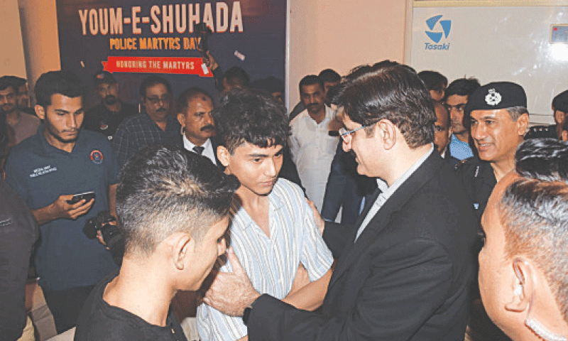 Chief Minister Murad Ali Shah interacts with the children of a martyred policeman during the ceremony at PAF Museum.&mdash;Dawn