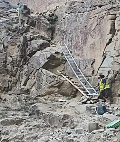  LOCAL volunteers use wooden ladders to transport relief goods to the stranded population through an old access way after the main road leading to Ghizer was blocked.—Dawn 