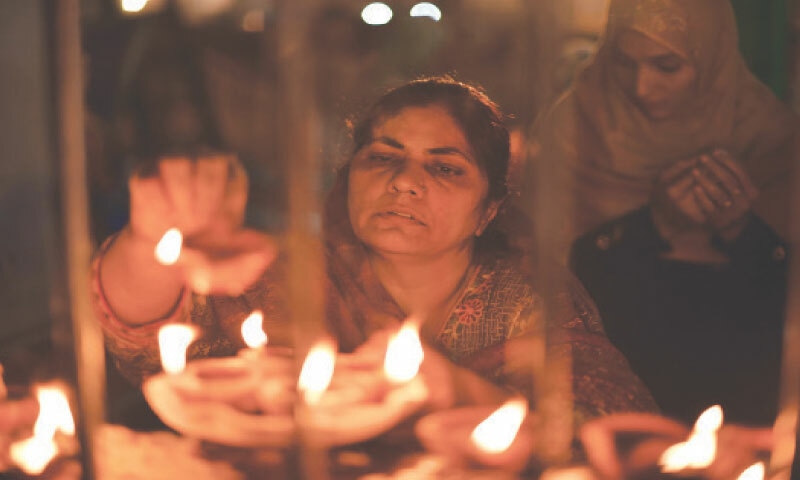  A woman lights a candle at Data Darbar in Lahore | Arif Ali/White Star 