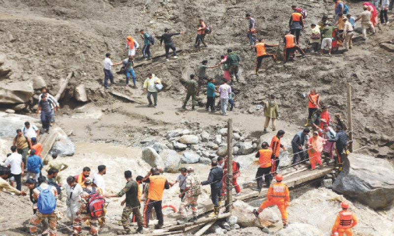 RESCUERS help stranded people cross a water channel using a makeshift bridge near Chisoti, a flood-devastated village in India-occupied Kashmir.—Reuters RESCUERS help stranded people cross a water channel using a makeshift bridge near Chisoti, a flood-devastated village in India-occupied Kashmir.—Reuters