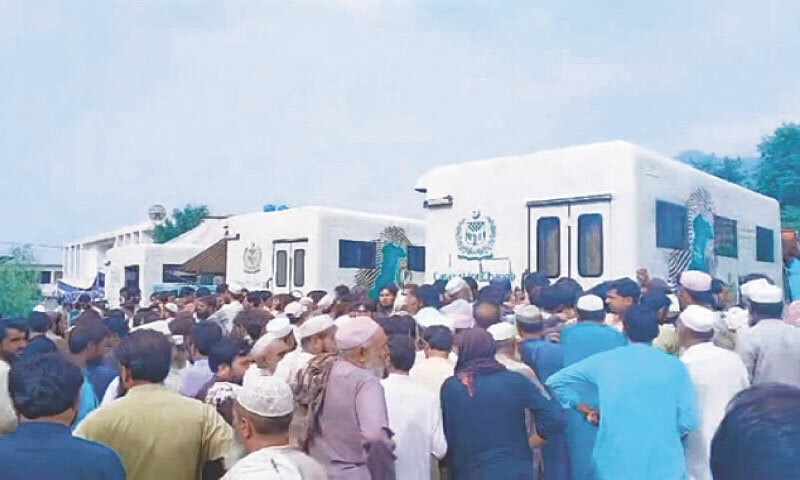 Displaced people wait outside a registration centre in Bajaur on Sunday. — Dawn Displaced people wait outside a registration centre in Bajaur on Sunday. — Dawn