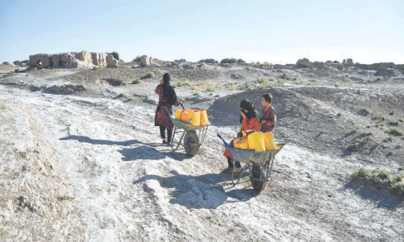AN Afghan woman and children haul water cans on wheelbarrows along a deserted street in the drought-ridden village of Bolak in Balkh province.&mdash;AFP/file