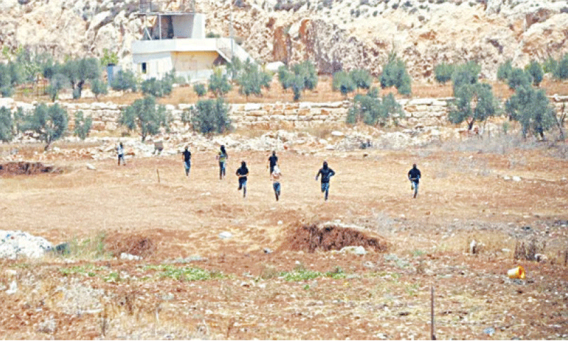 Masked settlers ran into the Palestinian farmland.&mdash;Courtesy BBC