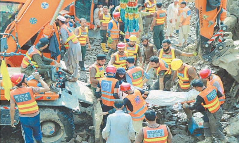 Rescue 1122 workers recover a body from flood debris in Dalori village of Swabi on Wednesday. &mdash; Photo by Muqaddam Khan