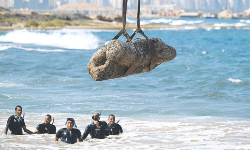 DIVERS watch as a crane pulls a piece of stone from the waters at Abu Qir bay in Alexandria.&mdash;AFP