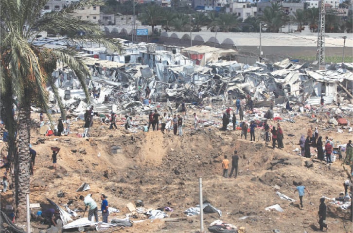  GAZA: Displaced Palestinians gather around a crater after an Israeli strike at a camp for internally displaced people, in Deir el-Balah..&mdash;AFP 