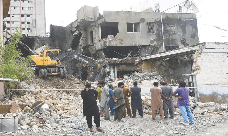 An excavator removes the rubble from the building damaged by the blast at a fireworks shop on M.A. Jinnah Road. &mdash;Shakil Adil/ White Star