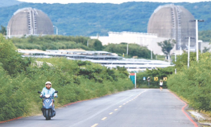 Pingtung (Taiwan): A person rides a vehicle as the Maanshan nuclear power plant stands in the background.—Reuters/file Pingtung (Taiwan): A person rides a vehicle as the Maanshan nuclear power plant stands in the background.—Reuters/file