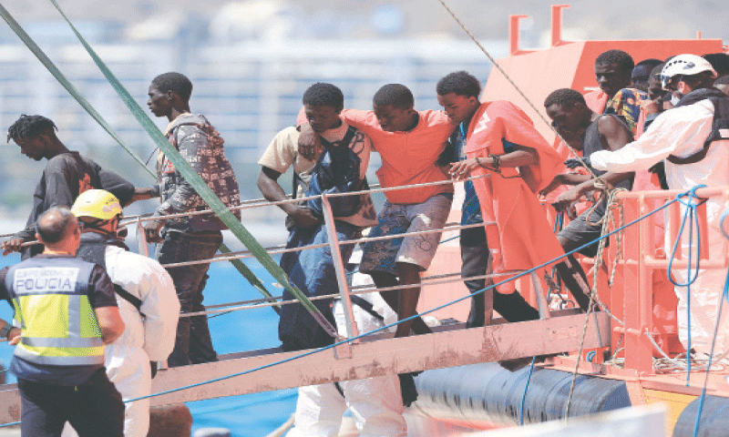 Migrants disembark from a Spanish coast guard vessel at the port of Arguineguin, on the island of Gran Canaria, on Sunday.&mdash;Reuters
