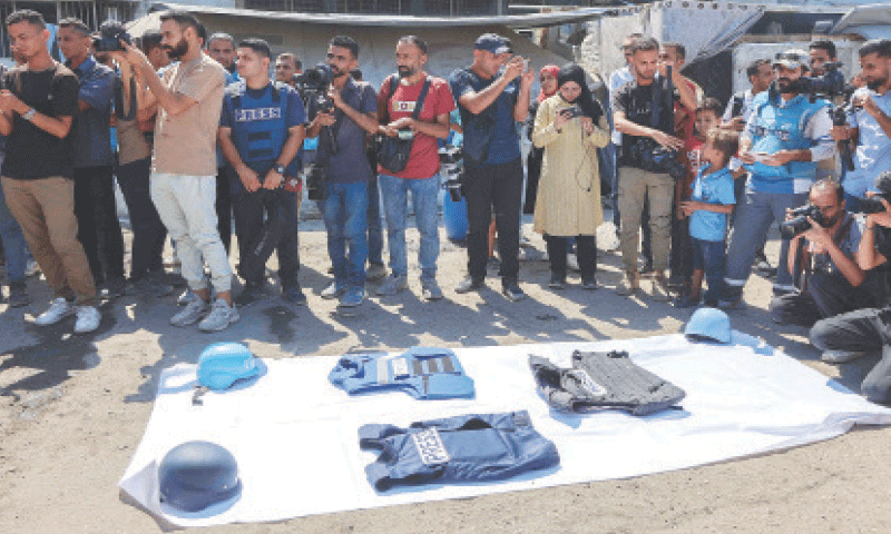 GAZA CITY: Members of the press gather around piece of protective gear, used by their slain colleagues, during a demonstration organised by the Gaza Journalists Syndicate.&mdash;AFP