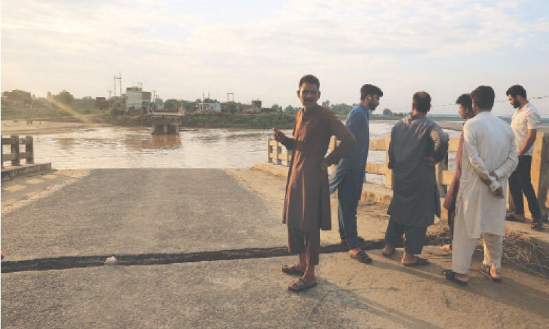 Residents stand on the remains of a collapsed bridge over Nullah Dek following monsoon rains and rising water levels in Zafarwal.—Reuters Residents stand on the remains of a collapsed bridge over Nullah Dek following monsoon rains and rising water levels in Zafarwal.—Reuters