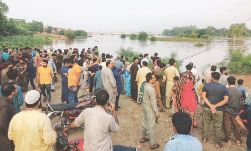 Residents of Farrukhabad stand on the banks of the river Ravi after the floodwater enters their locality. — White Star