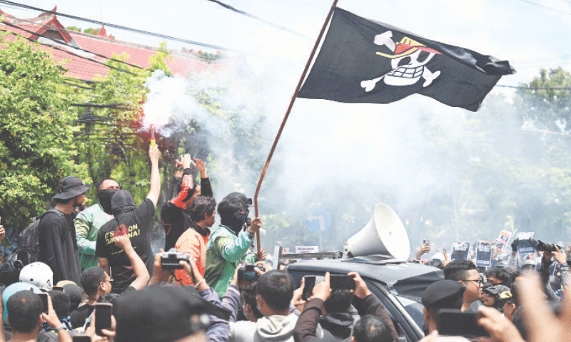 PROTESTERS hold a flare and wave a pirate flag, evoking the Japanese anime One Piece, during a demonstration in front of a police station in Denpasar, Bali.&mdash;AFP