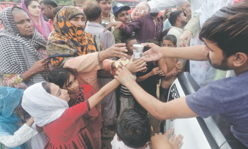 LAHORE: Women who fled their homes on the flooded banks of the Ravi, gather to receive tea distributed by volunteers at a relief camp.—Reuters LAHORE: Women who fled their homes on the flooded banks of the Ravi, gather to receive tea distributed by volunteers at a relief camp.—Reuters