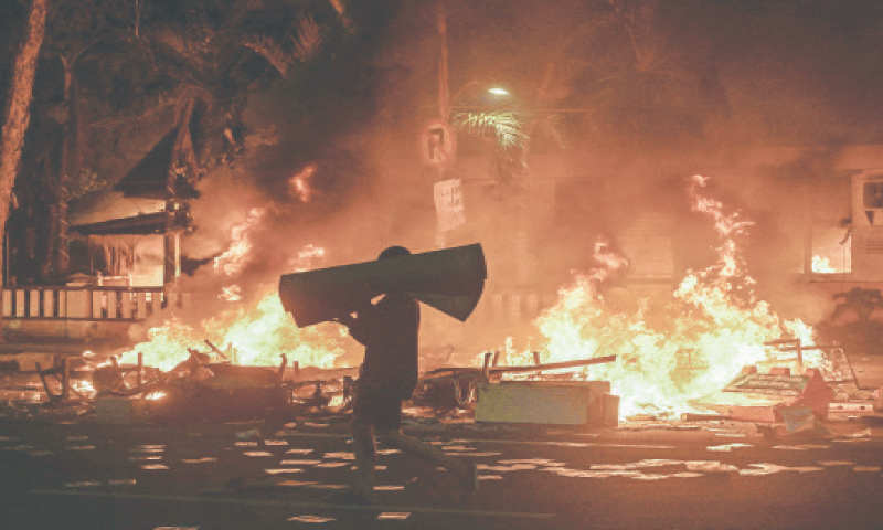SURABAYA: A protester carries looted goods on a street in front of a police headquarters that was set on fire and looted during demonstrations on Sunday.&mdash;AFP