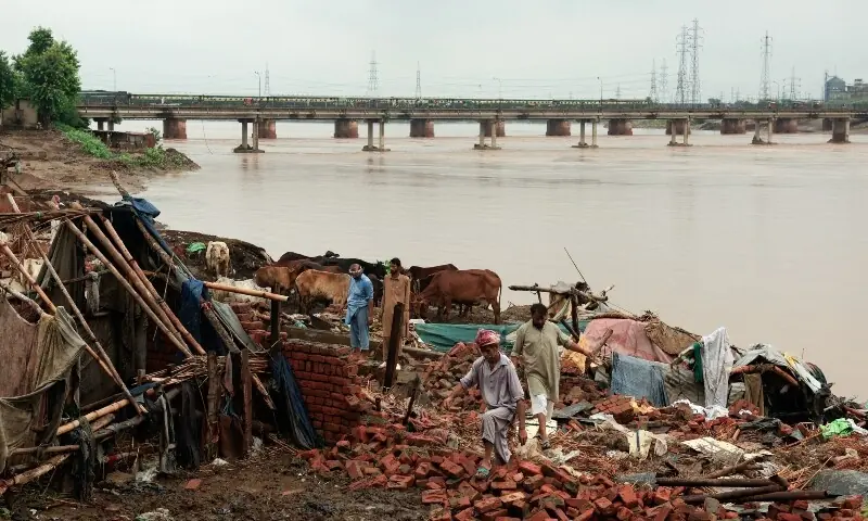 Residents inspect the remains of damaged property after water levels receded along the right bank of the Ravi River, Lahore, August 31. — Reuters