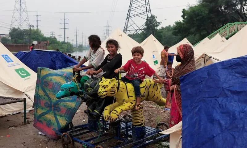 Children whose families fled from a flooded area, play while taking shelter in makeshift tents, following recent floods caused by monsoon rains, in Lahore on August 31. &mdash; Reuters