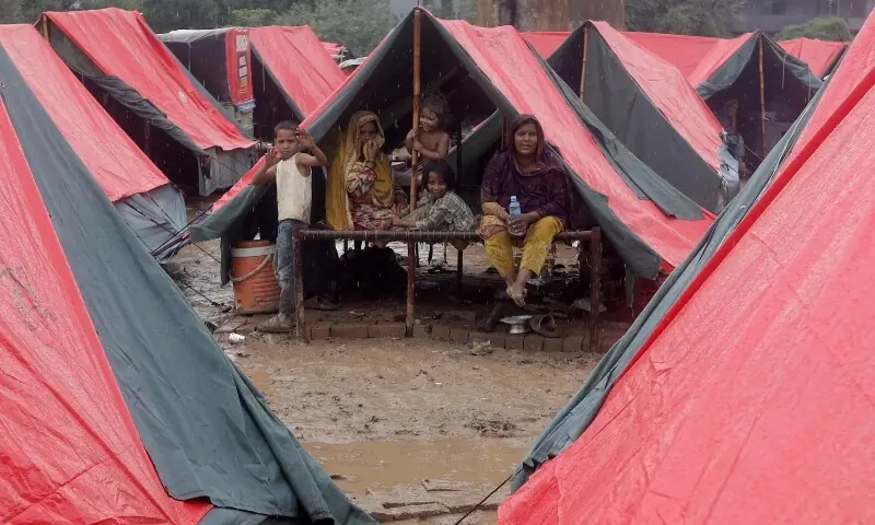 Members of a family, who fled from flooded banks of Ravi River, take shelter in a tent at a relief camp in Lahore on August 31. &mdash; Reuters
