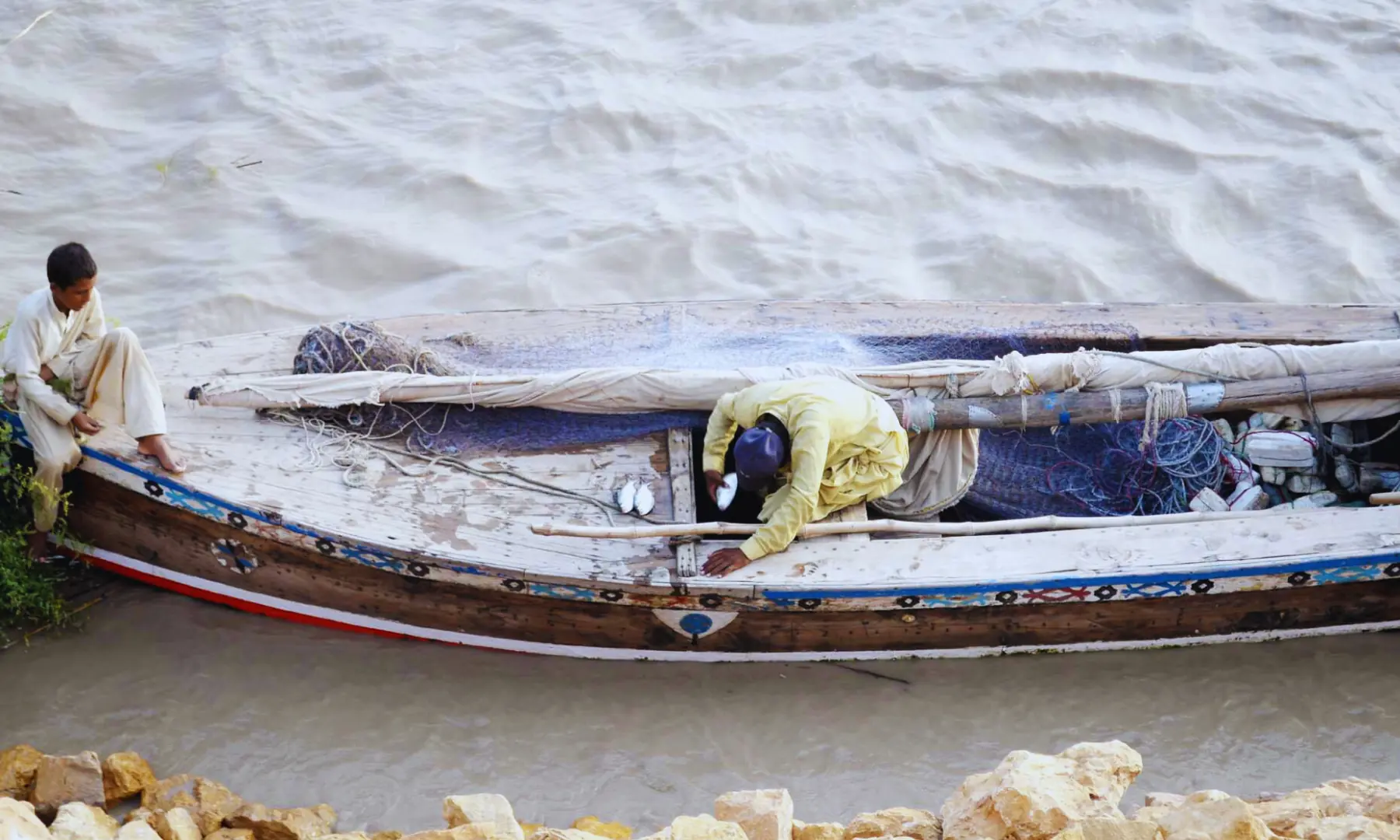 Several wooden boats with fishermen on boat busy in fishing in Indus river downstream Kotri barrage.