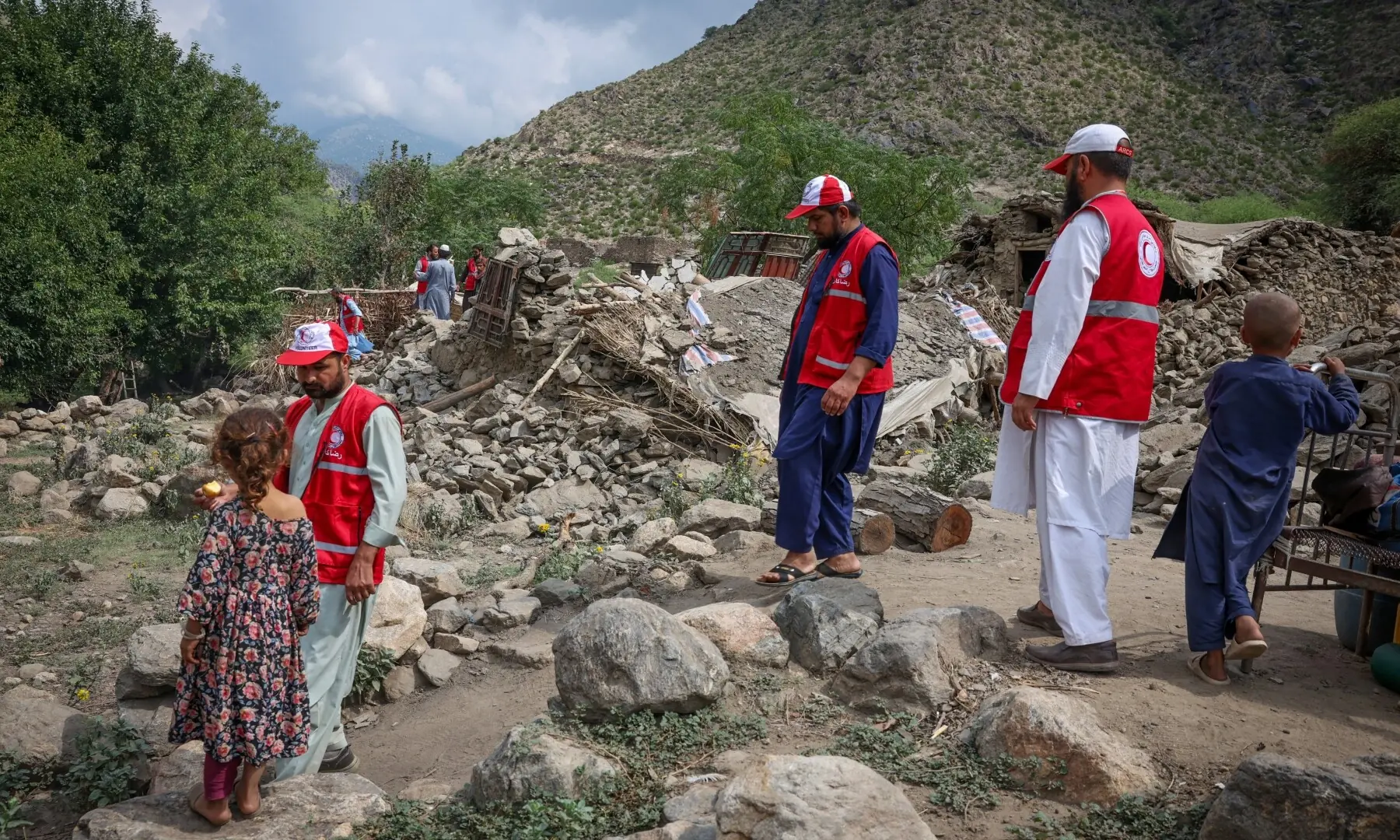 Red Crescent volunteers walk next to damaged houses as they reach Lulam village to help the victims following a deadly magnitude-6 earthquake that struck Afghanistan on Sunday, in Nurgal district, Kunar province, Afghanistan on September 3. — Reuters