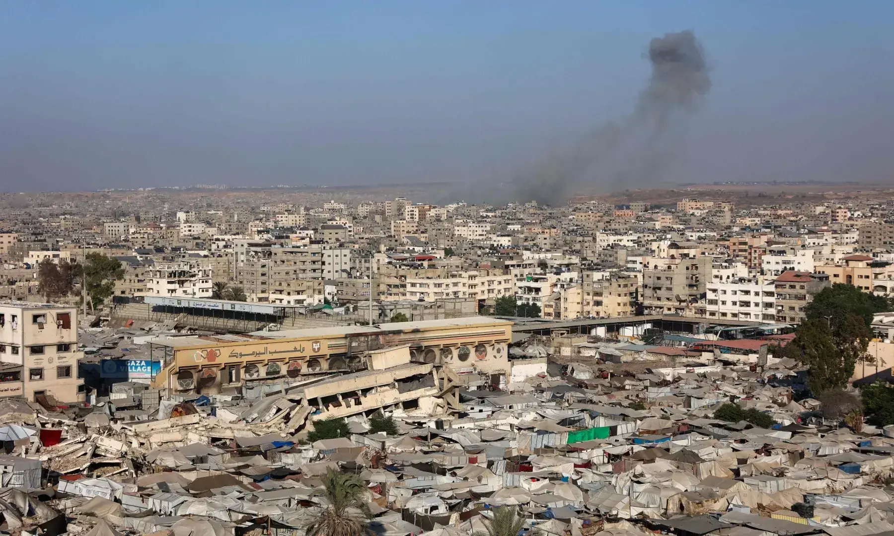 A picture shows a view of a makeshift displacement camp at the Yarmuk Sports Stadium, once a football arena, as smoke billows during Israeli strikes on Gaza City on September 4, 2025. &mdash; AFP