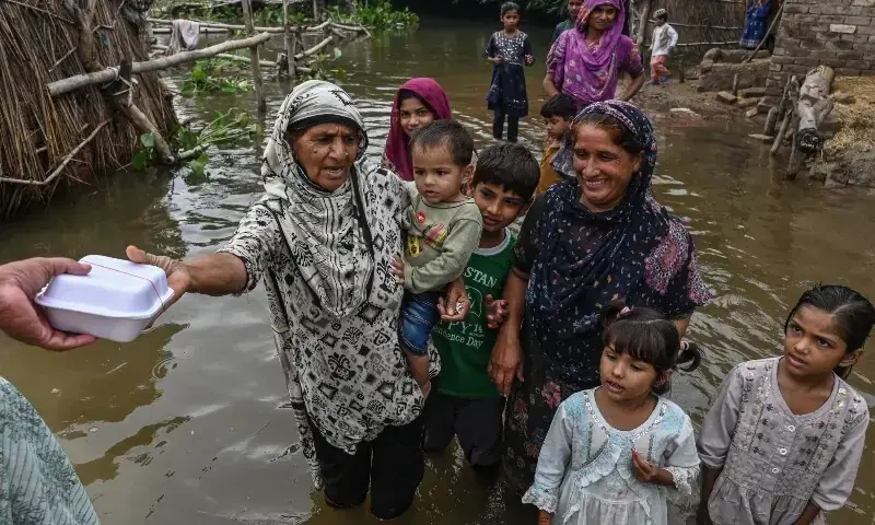 Villagers receive food aid in the flood-affected area of Bheki Wala village in Kasur district on August 24. &mdash; AFP/File