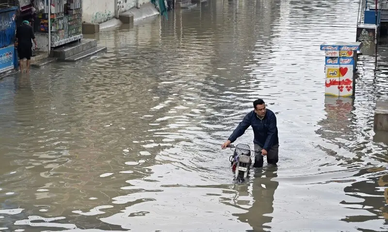 A motorcyclist wades through a flooded street after heavy rainfall in Karachi, Sept 10. &mdash; AFP