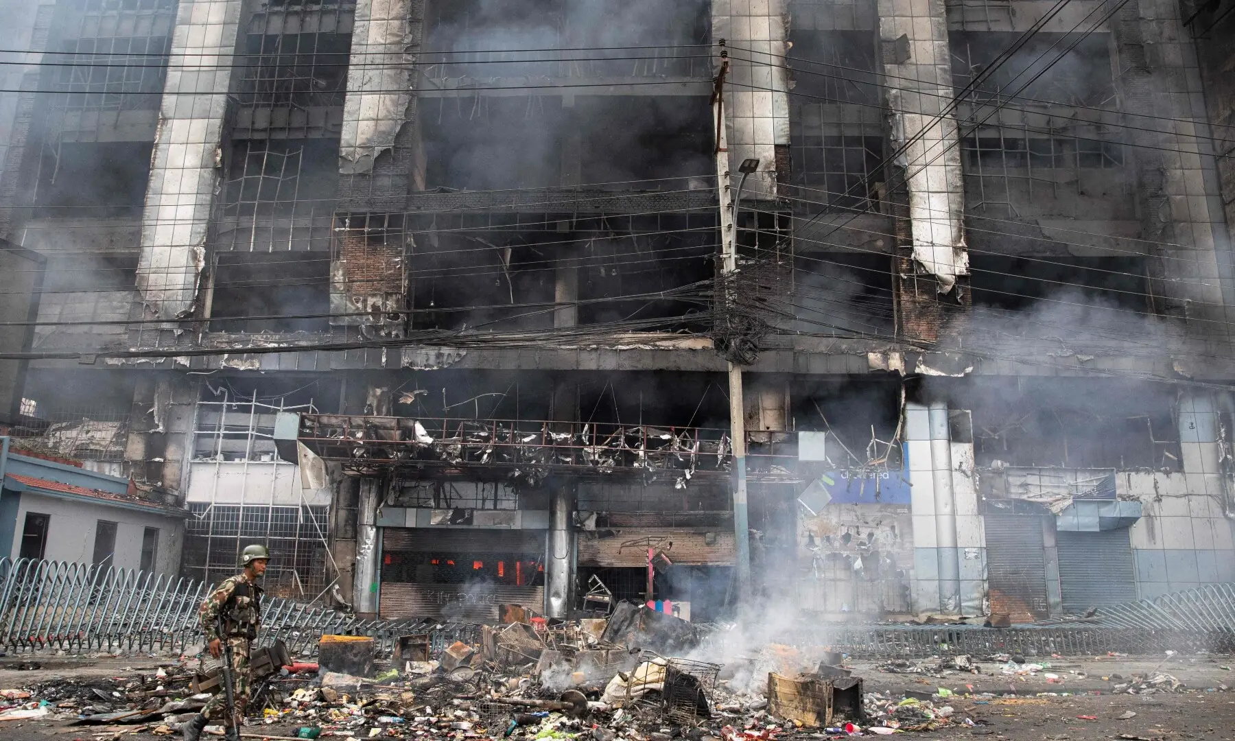 An Army personnel patrols along a street as smoke billows from a burning supermarket building of Nepal’s renowned retail chain Bhat-Bhateni, a day after it was set ablaze by protesters in Kathmandu on September 10, 2025. — AFP