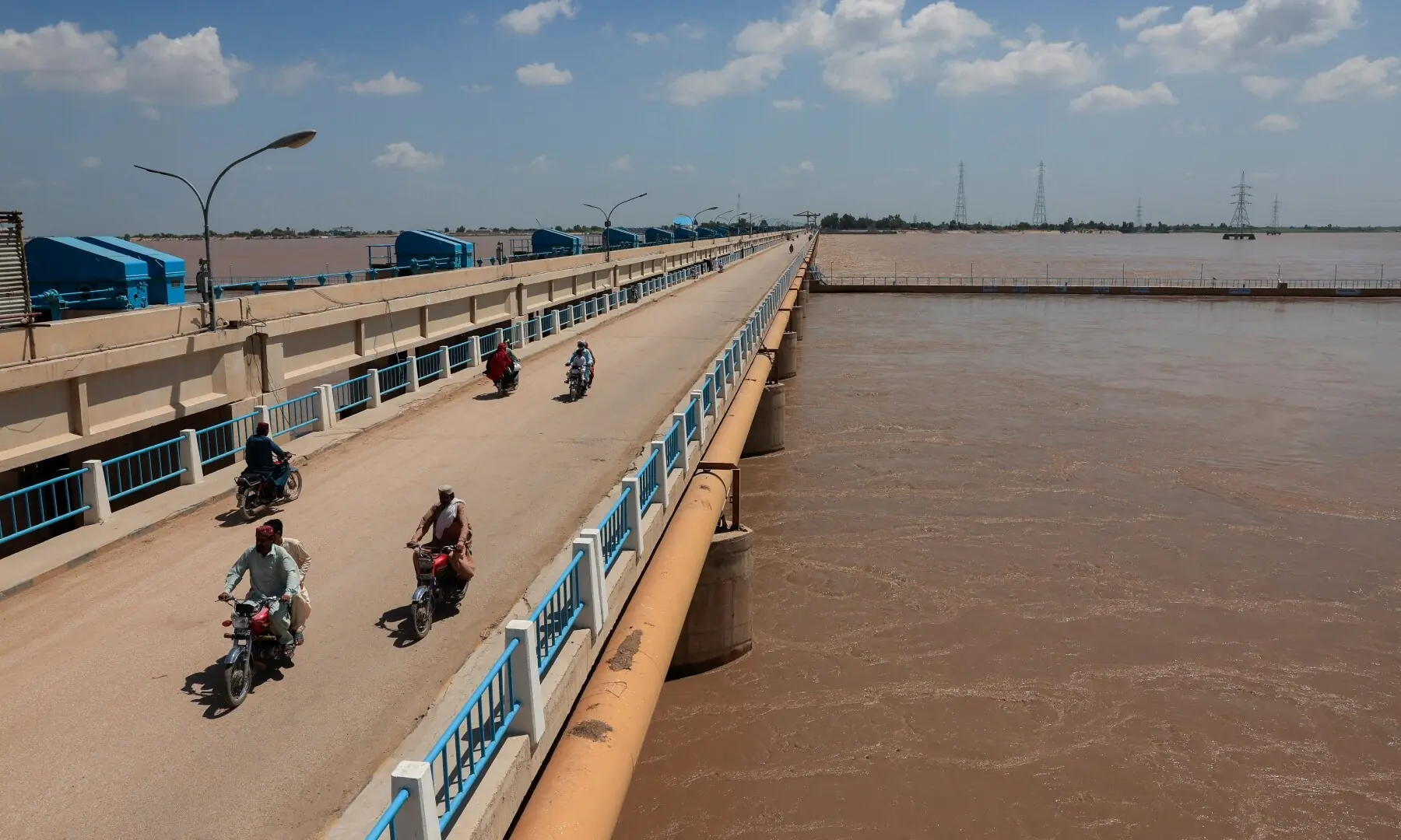 Commuters on motorbikes ride along the Guddu Barrage as floodwater passes through, following monsoon rains and rising levels of Indus River, in Kashmore, Sindh on Sept 13, 2025. &mdash; Reuters/Akhtar Soomro 