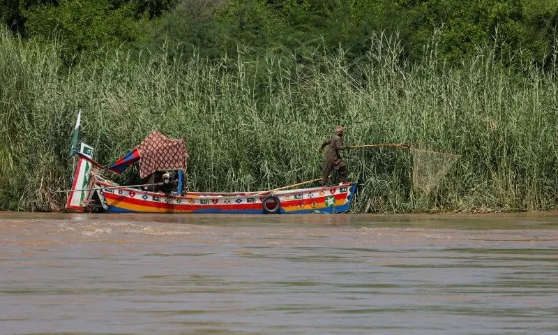A fisherman uses a net to catch fish on his boat as floodwater passes through, following monsoon rains and rising levels of the Indus River in Sukkur on Sept 14. &mdash; Reuters