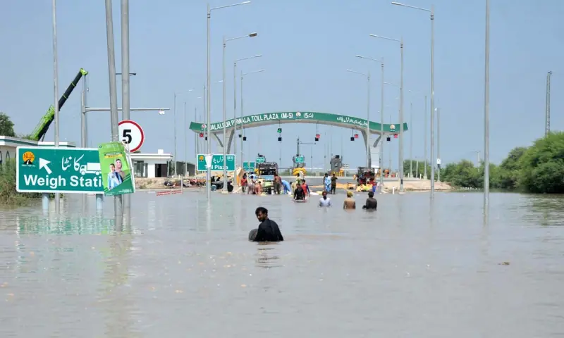  People wade through waist-deep water as the entrance to the M5 (Multan-Sukkur) motorway is submerged, causing problems for traffic on this key national artery. &mdash; APP 