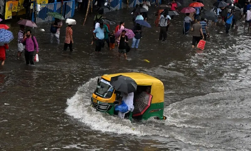 Commuters wade across a waterlogged street after heavy monsoon rains in Kolkata on September 23. &mdash; AFP