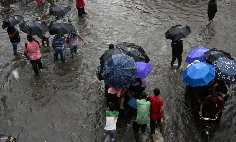 Commuters wade across a waterlogged street after heavy monsoon rains in India&rsquo;s Kolkata on September 23. &mdash; AFP