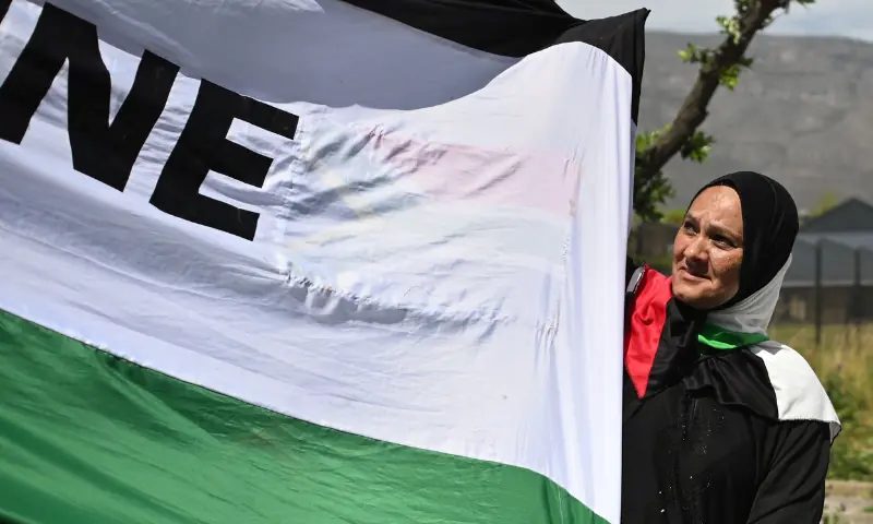 A protester holds a large Palestinian flag as she marches through the city centre during civil society and faith-based organisations&rsquo; mass rally for Gaza, in Cape Town on September 27, 2025. &mdash; AFP